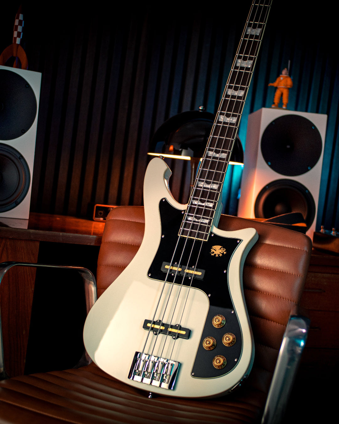 Electric Nidhogg bass guitar on a chair with speakers and curtain in the background