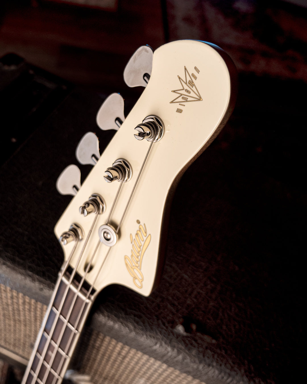 Close-up of a Wingman bass headstock with Baum logo against a dark background