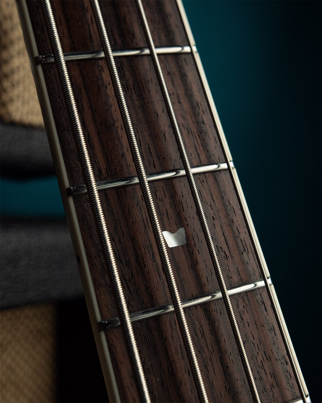 Close-up of a Wingman bass fretboard with strings